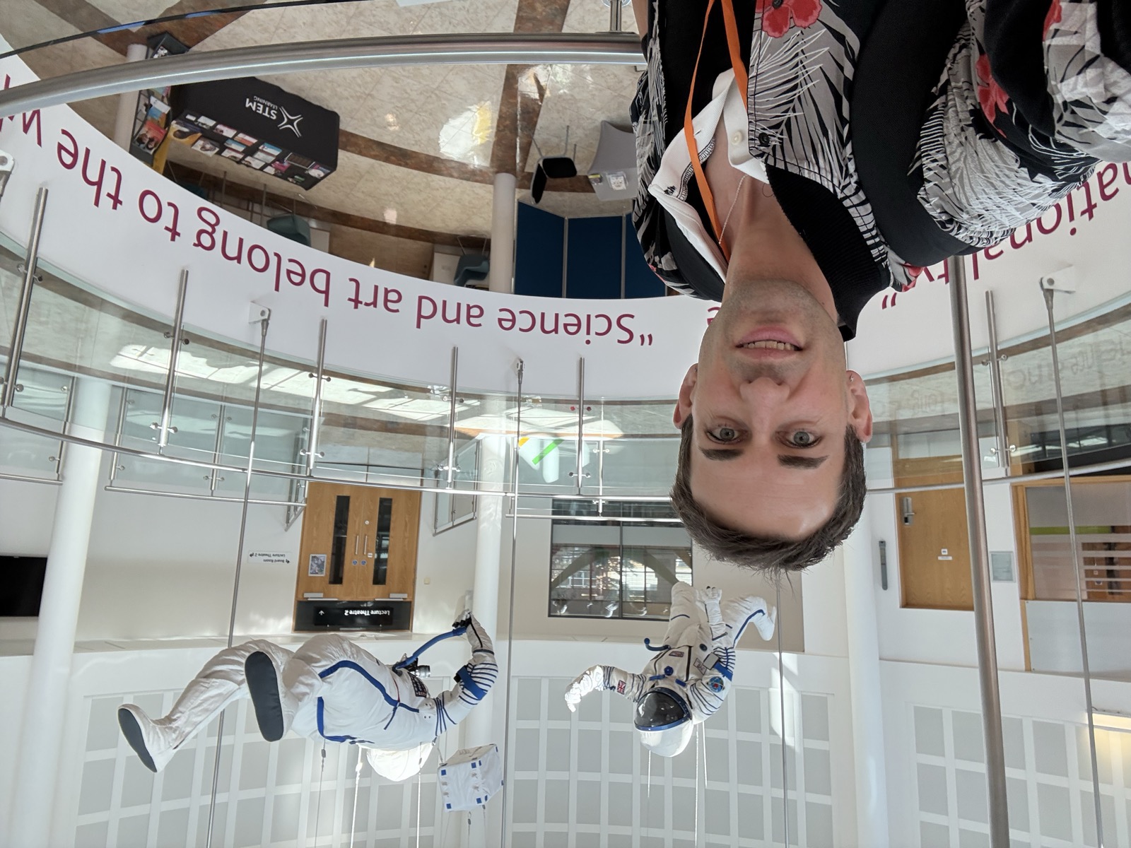 Eve Anderson at a STEM venue, with two cosmonaut spacesuits and a "Science and art belong to the nation" banner behind her